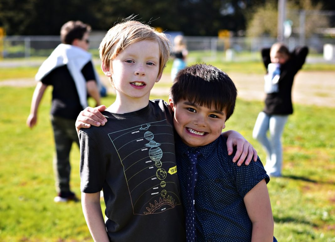 two young boys pose for a photo with their arms around each other
